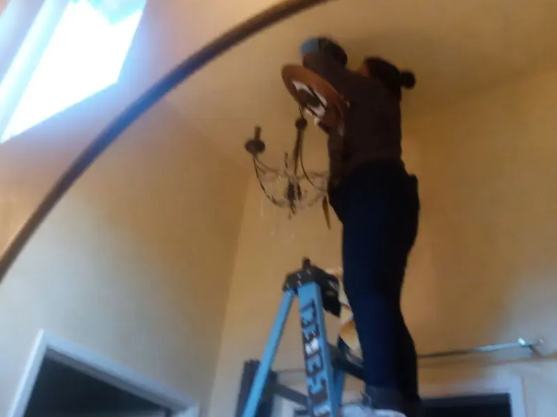 Electrician installing a chandelier in a Plano residence